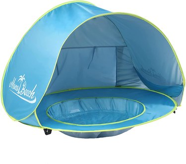 Baby beach tent enclosed on three sides with a tiny "pool" in the middle where a baby can play with sand or water.