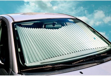 Dash Designs Universal Retractable Windshield Sun Shade in the windshield of a sedan.