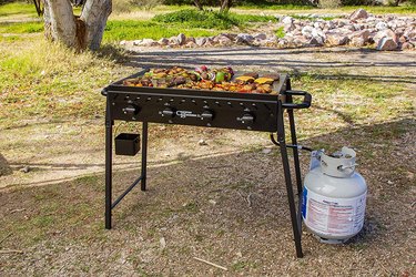 Country Smokers Highland 4-Burner Portable Griddle hooked up to a propane tank outdoors.