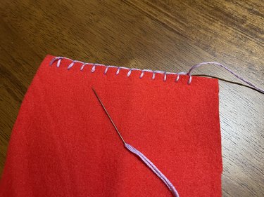 A piece of red fleece with a purple thread blanket stitch