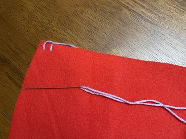 A piece of red fleece with a purple thread blanket stitch