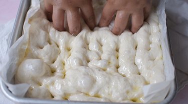 Dimpling focaccia dough with fingers