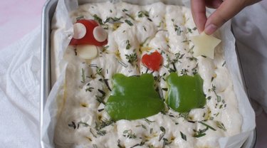 Adding toppings to focaccia dough