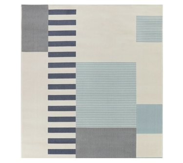 Geometric area rug with light blue, dark blue, and gray striped/block designs with an off-white base color.