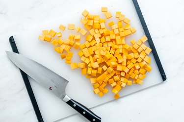 cutting butternut squash with a knife on a cutting board.