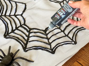 drawing a spiderweb on tulle with puffy paint