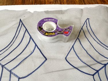 securing black tulle over spiderweb drawing with tape