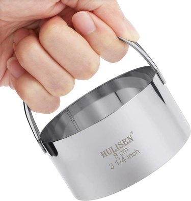 Hand holding a Hulisen stainless steel cookie and biscuit cutter, 3 1/4 inch size, demonstrating the size and comfort of its handle
