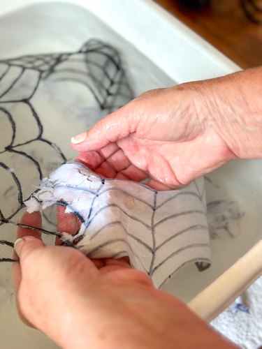 dipping spiderweb necklace in water and removing paper from back