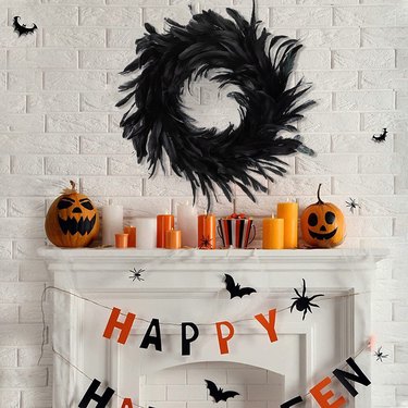 Black Feather Wreath from Amazon above a fireplace mantle decorated for Halloween.