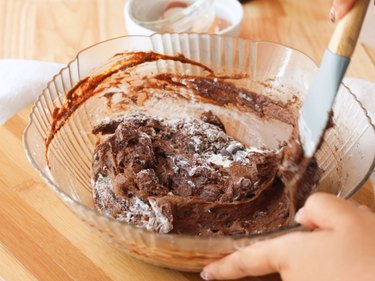 Using a silicone spatula to fold in dry ingredients and chocolate chips to batter