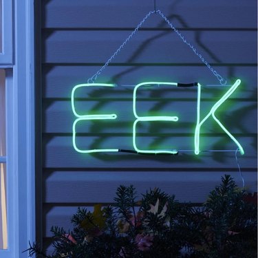 Eek Lighted Sign from Wayfair. The letters are green and it hangs from a metal chain that connects to the two ends.