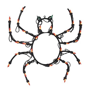 Pre-Lit Spider Halloween Decoration from Bed Bath & Beyond. The outline of the spide is black and it has orange bulbs and green bulb eyes.