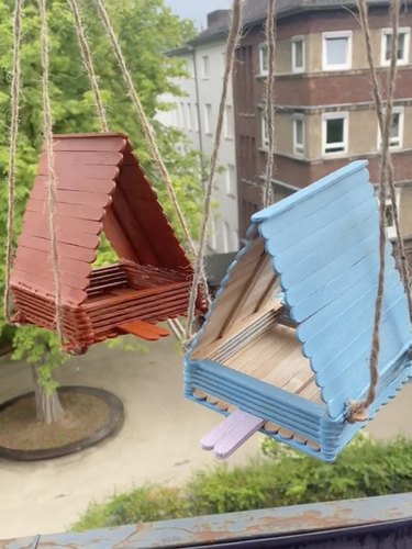 Two birdhouses made from popsicle sticks, one red and one light blue