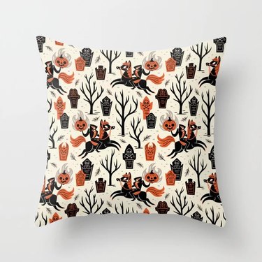 Halloween throw pillow from Society6 with designs of the headless horseman and spooky graves and trees.