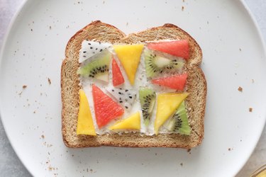 Toast with cream cheese and fruit triangles on a white plate
