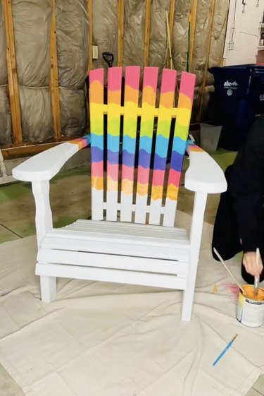 White Adirondack chair painted with rainbow design