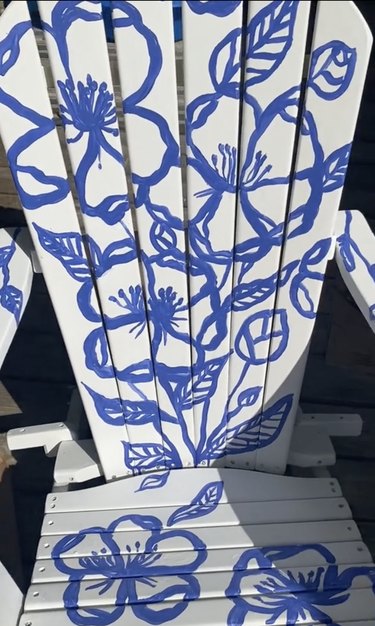 White Adirondack chair painted with blue flower designs