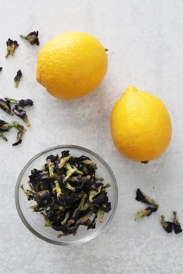 Dried butterfly pea flowers and lemons on a gray background