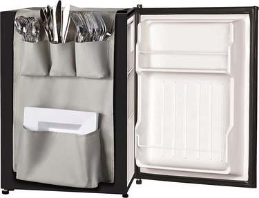 Light gray over-the-fridge organizer with different sized pockets for things like plates, utensils, and snacks.