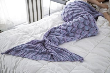 Purple mermaid tail blanket draped across legs