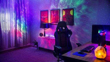 PC gaming room with laser star projection on walls in shades of blue, green, and pink with tiny white "stars."
