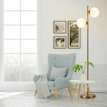 Brass-finish floor lamp with two frosted glass dome lights on either side, one higher than the other.