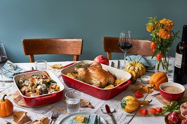 An autumn table with a roasted chicken in a large Staub baking dish, and a side dish in a second, smaller staub