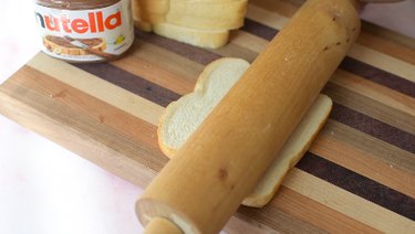 Flattening a bread slice with a rolling pin