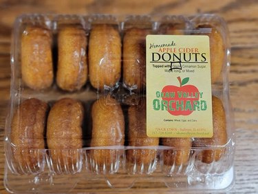 One dozen apple cider donuts in a clear plastic container