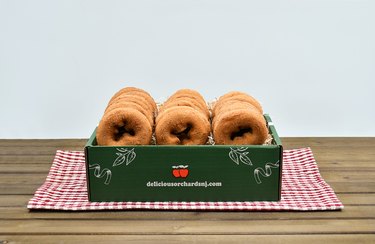 Apple cider donuts in a green box atop a red-and-white checkered cloth