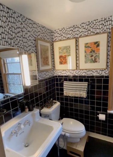 Bathroom with black tile and black-and-white wallpaper next to a white toilet