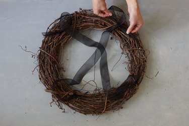 tying black ribbons to grapevine wreath