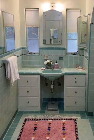 Bathroom with bright blue tiles and a pink rug featuring multicolored triangles