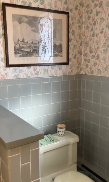 Bathroom featuring light blue tiles and floral wallpaper