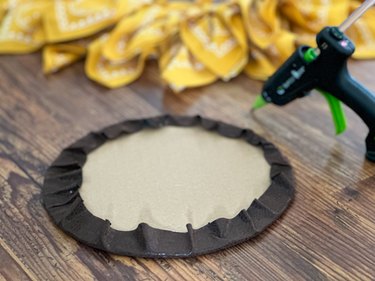 attach fabric to cardboard circle using a hot glue gun