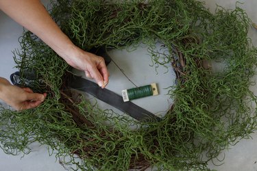 tying moss garland to wreath with floral wire