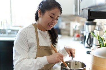 Kat Lieu in an apron cooking in her kitchen