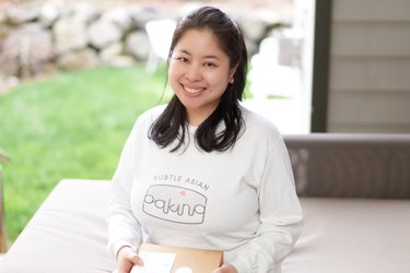 Kat Lieu, founder of Subtle Asian Baking and author of Modern Asian Baking at Home, poses outside wearing a shirt that says "Subtle Asian Baking"