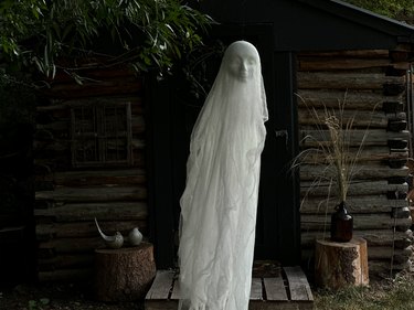 finished cheesecloth ghost floating in front of an old shed