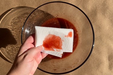 A hand holding a paper towel with fake blood