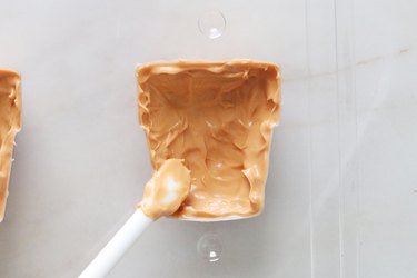 Spreading melted pumpkin spice candy in a plant pot candy mold