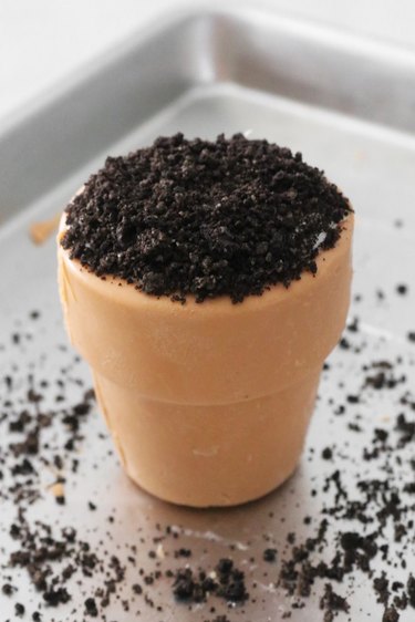Candy pot topped with frosting and Oreo crumbs