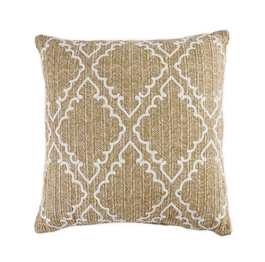 Square throw pillow with tan, natural-looking woven fabric with a pattern that resembles diamond cut-out shapes with curly edges.