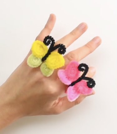 Hand displaying two butterfly-shaped rings made from pipe cleaners