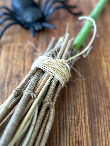 wrap twine around bristles to hold them in place around the broom handle