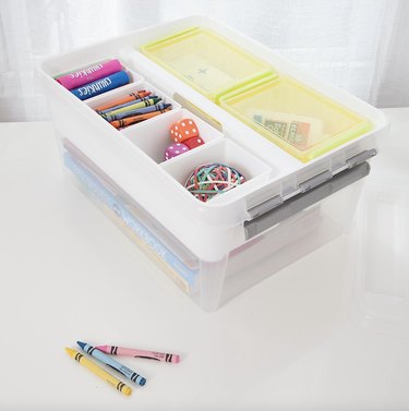 Plastic storage container with school supplies in compartments