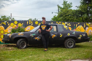 Nicole standing by an upcycled car that's been turned into a pollinator garden
