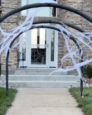 Entryway to a home made from black pool noodles and fake cobwebs