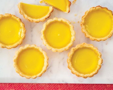 Half a dozen Hong Kong egg tarts lined up in a lovely (and tasty) geometric pattern with the top tart cut in half